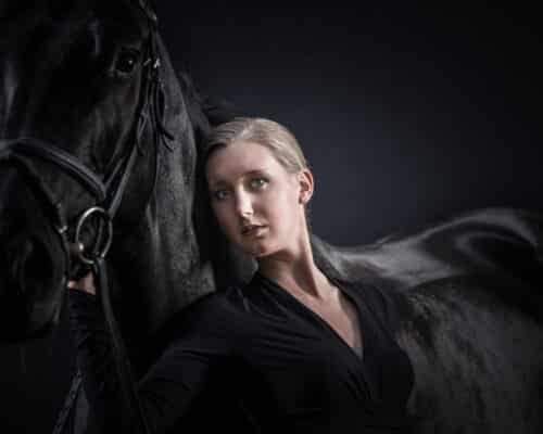 Frau posiert vor schwarzem Pferd