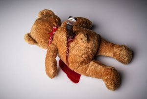 Teddybär mit Messer im Rücken und Blut