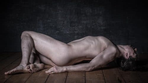 Mann liegt nackt auf dem Boden